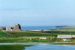 Noltland Castle with the North Atlantic in the distance and Burness Loch in the foreground